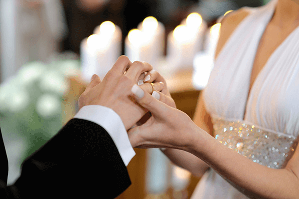 Невеста одевает кольцо жениху.