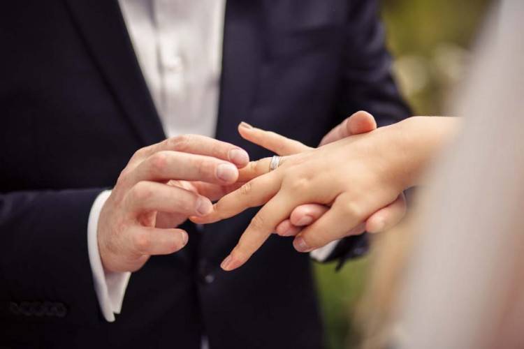 Жених надевает обручальное кольцо на руку невесты